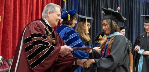 Graduate degree student receiving diploma from President Warner